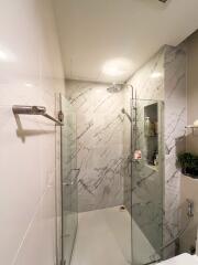 Modern bathroom with glass shower door and marble tiles