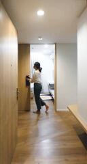 Person walking through a modern hallway with wooden flooring and bright lighting