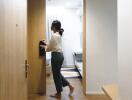 Person walking through a modern hallway with wooden flooring and bright lighting