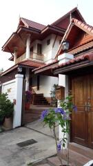 Two-story traditional house with wooden elements and a garden