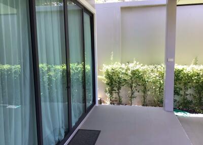 Outdoor patio area with sliding glass door and greenery