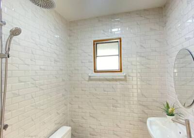 Modern bathroom with white tiles, shower, toilet, and sink