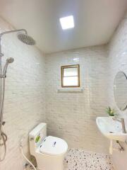 Modern bathroom with white tiles, shower, toilet, and sink