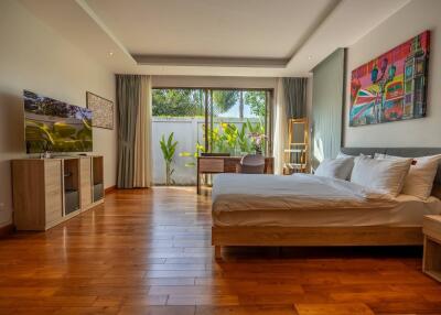 Spacious and well-lit bedroom with wooden flooring and modern decor