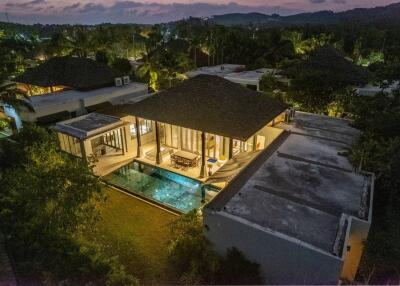 Aerial view of a modern villa with a swimming pool at sunset