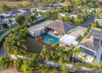 Aerial view of a luxurious property with a swimming pool, greenery, and multiple buildings