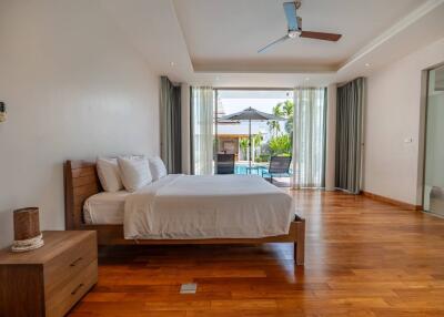 Spacious bedroom with wooden flooring and a view of the pool