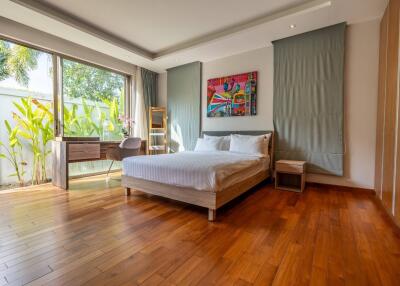Spacious bedroom with wooden floors, large window, and modern furnishings