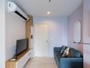 Modern living room with a wall-mounted air conditioner, blue sofa, and TV stand