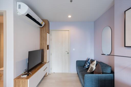 Modern living room with a wall-mounted air conditioner, blue sofa, and TV stand