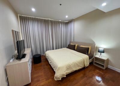 Bedroom with wooden flooring, bed, TV, and nightstand