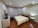 Bedroom with wooden flooring, bed, TV, and nightstand