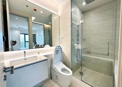 Modern bathroom with a large mirror, built-in sink, toilet, and a glass-enclosed shower