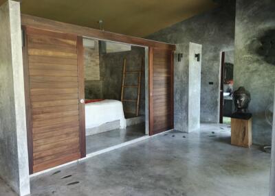 Modern and rustic bedroom with sliding wooden doors and concrete flooring