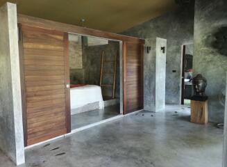 Modern and rustic bedroom with sliding wooden doors and concrete flooring