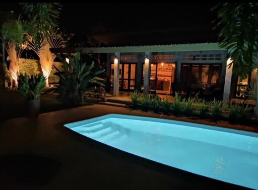 Outdoor night view with illuminated pool and house