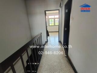 Hallway leading to a well-lit room with large windows