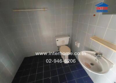 Bathroom with toilet, sink, and tiled walls