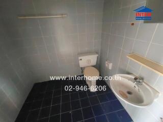 Bathroom with toilet, sink, and tiled walls