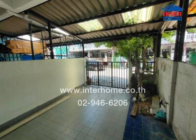 Covered carport area with a small garden and metal gate