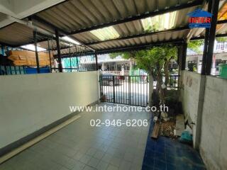 Covered carport area with a small garden and metal gate