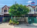 Exterior view of two-story residential building with fenced front yard and potted plants