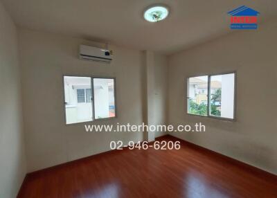 Empty bedroom with wooden flooring and air conditioner