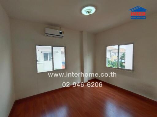 Empty bedroom with wooden flooring and air conditioner