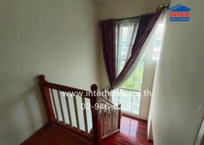 Staircase with wooden railing and window with curtains