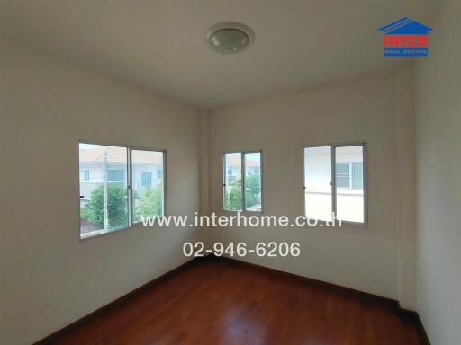 Empty bedroom with wooden floor and multiple windows