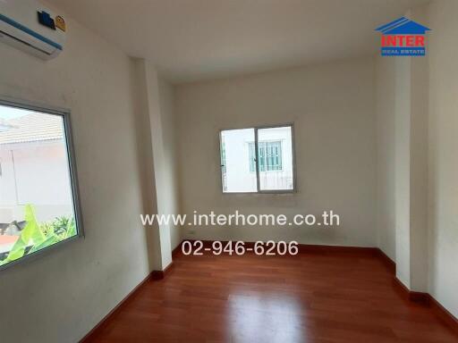 Empty room with wooden floor and two windows