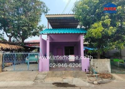 Front view of a small purple building with a teal roof and a gated entrance