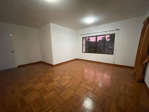 Spacious empty bedroom with wooden flooring and large window