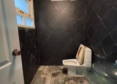 Bathroom with dark tiled walls, marble flooring, and a glass sink
