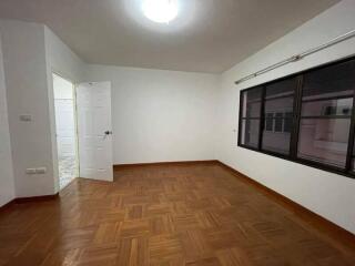 Spacious empty bedroom with wooden floor and large window