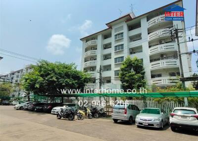 Exterior view of a residential building with parked cars and motorcycles in front