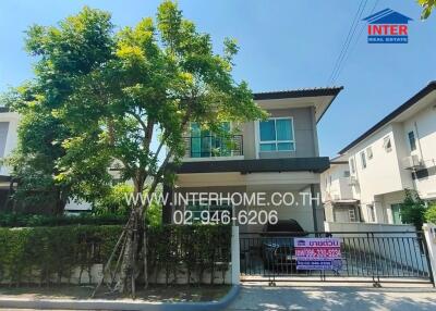 Two-story residential building with surrounding greenery and fence