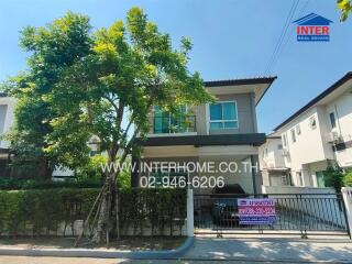 Two-story residential building with surrounding greenery and fence