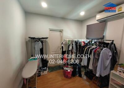 A small walk-in closet or laundry area with clothes racks and ironing board
