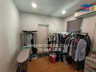 A small walk-in closet or laundry area with clothes racks and ironing board