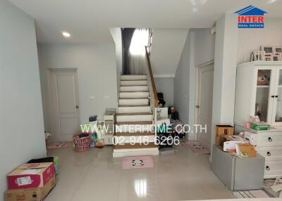 A well-lit living room with a staircase and various items.