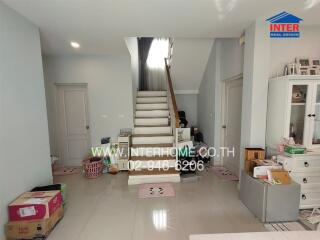 A well-lit living room with a staircase and various items.