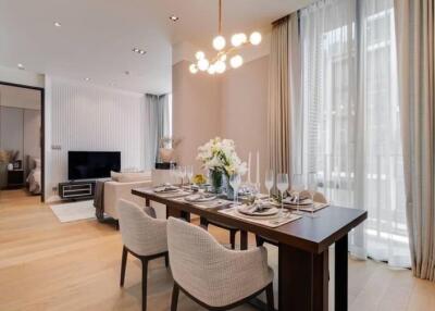 Modern living and dining area with a stylish chandelier, dining table, TV, and sofa