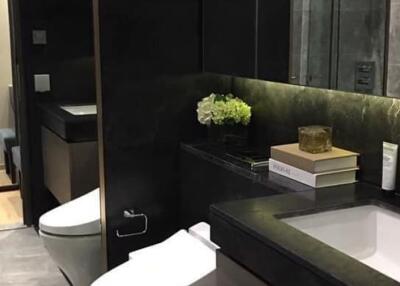 Modern bathroom with black finishes, a mirror, a toilet, a sink, and decorative items