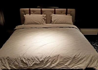 Bedroom with a padded headboard and beige bedding