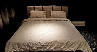 Bedroom with a padded headboard and beige bedding