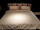 Bedroom with a padded headboard and beige bedding