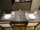 Dining table set for two with white dishes and glasses