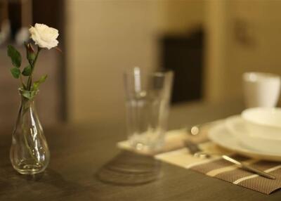 Close-up view of a dining table with a flower vase, glasses, and tableware