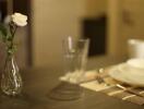 Close-up view of a dining table with a flower vase, glasses, and tableware